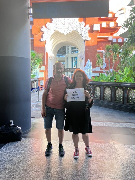 A couple posing with her name in front of Bali Airport